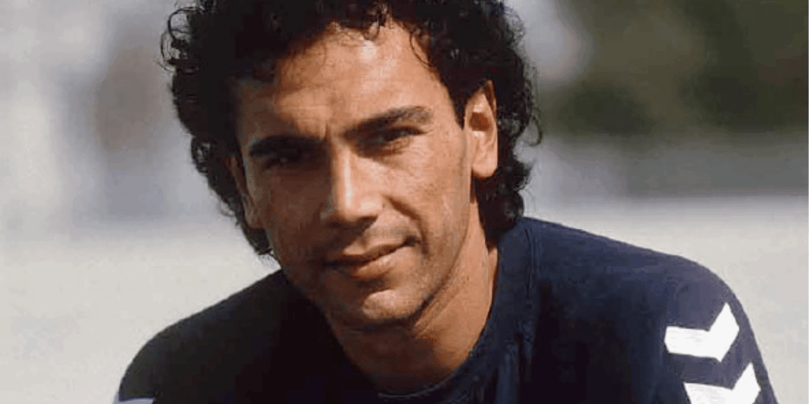 Close-up of a Man with Dark Curly Hair Wearing a Navy Shirt, Outdoors Near a Beach. - Regio Politica