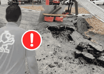 Person Standing Near a Large Sinkhole in a Street with a Red Warning Exclamation Icon on the Foreground. - Regio Politica